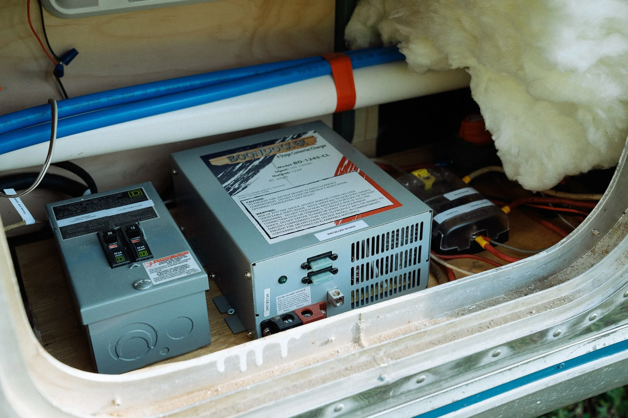 Electrical components and wiring inside a space or compartment with insulation insulation and piping.
