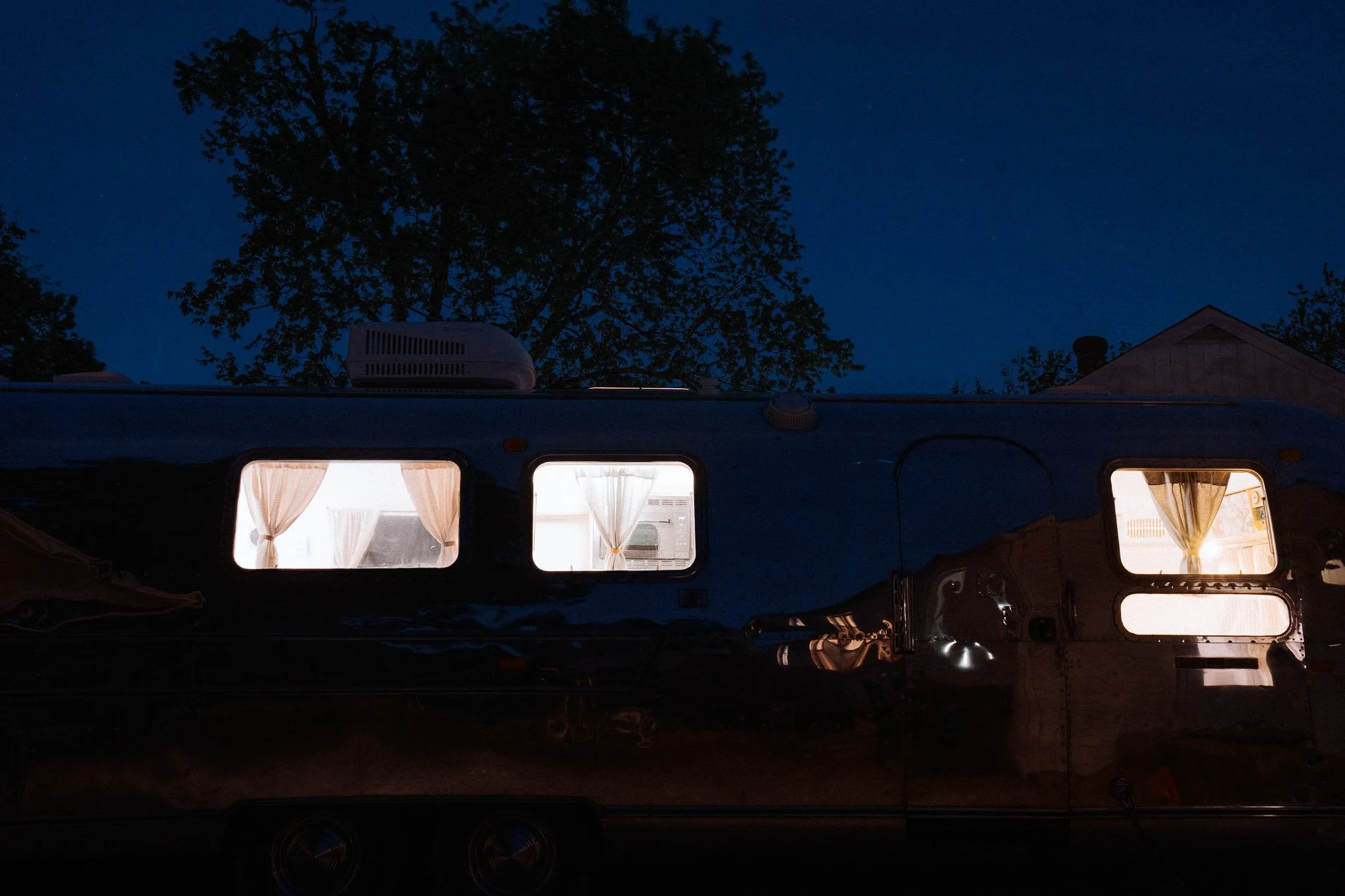 Aerial view of a dark Airstream with illuminated windows at night