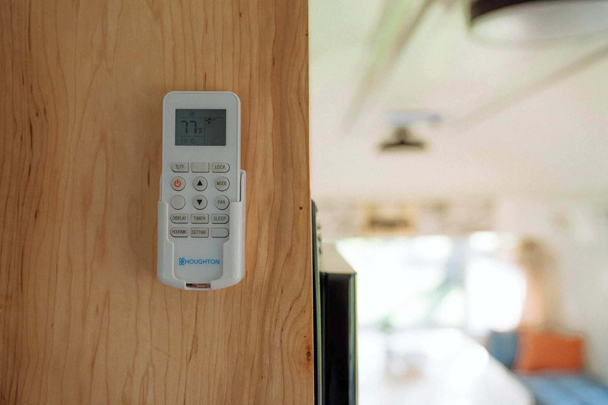 Remote control mounted on a wooden divider with a room visible in the background.