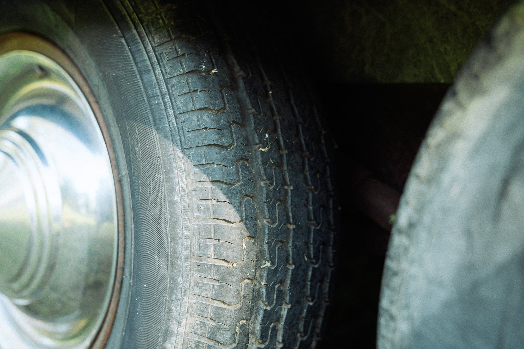 Close-up of a car tire with a wheel rim, showing details of the tread and sidewall, mounted on a vehicle.