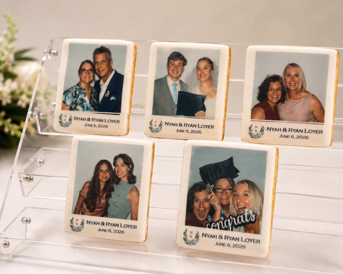 Cookies decorated with photos of a couple, Nyah and Ryan Loyer, at their wedding on June 6, 2026, arranged on a clear display stand with flowers nearby.
