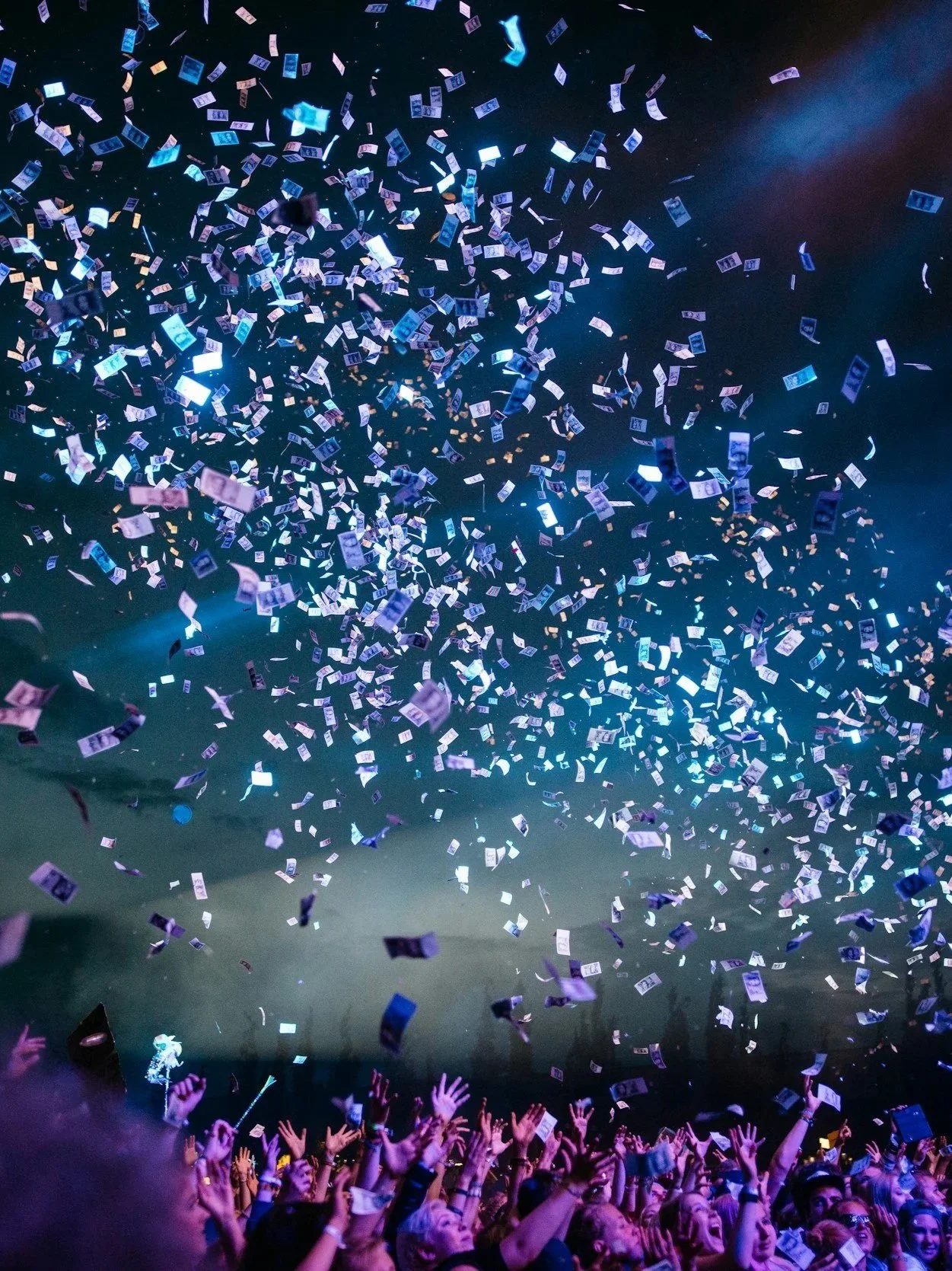 Crowd of people at a concert or event with confetti falling from above.