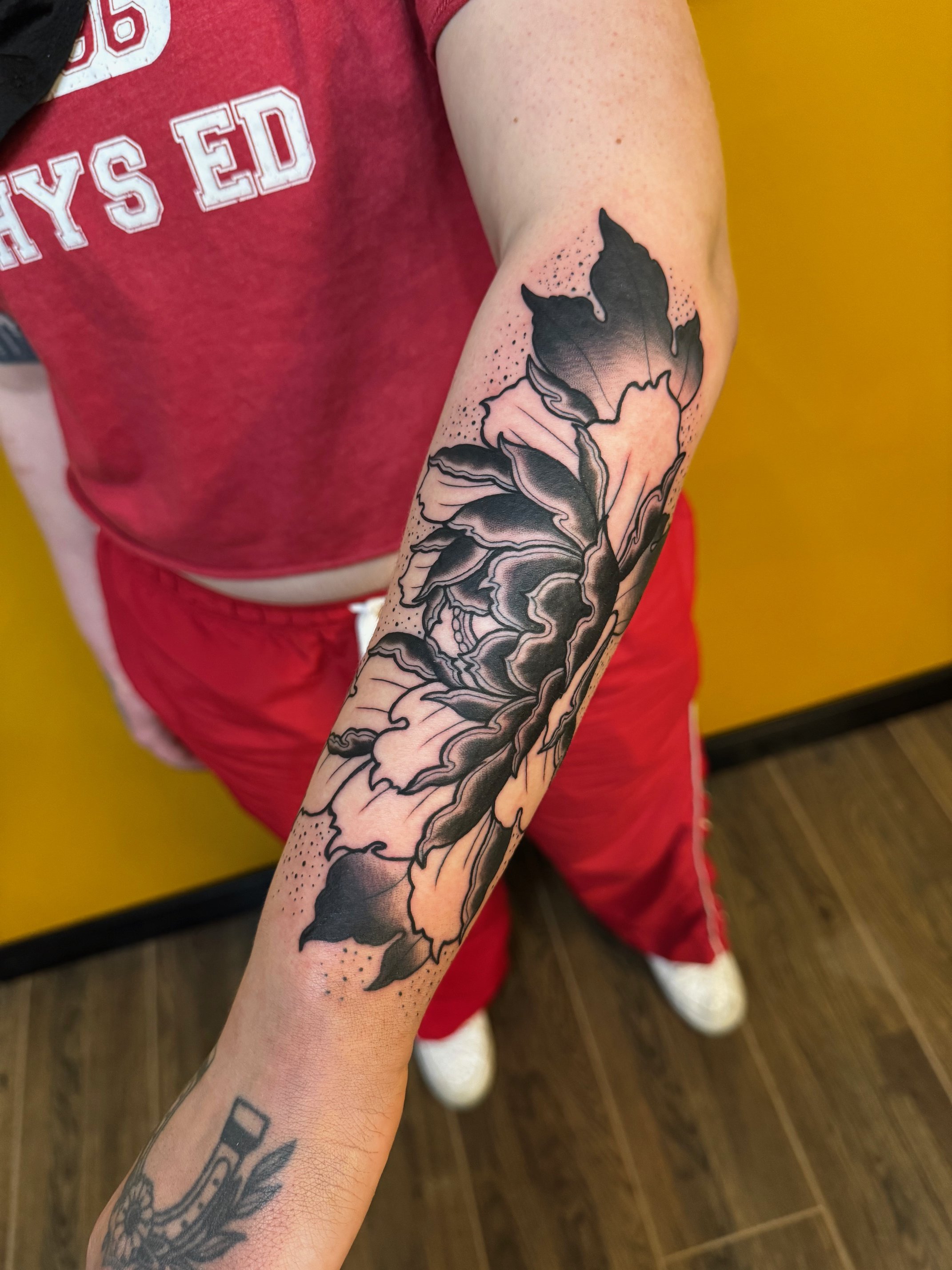 Tattoo of flowers on the forearm, with bold black details completed near the Lakewood area.