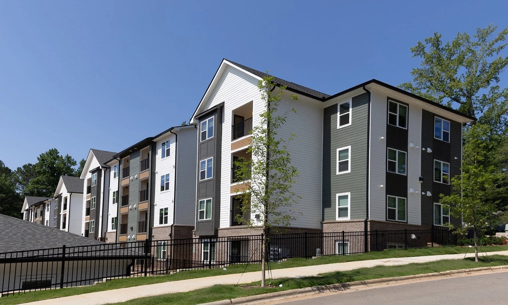 Exterior of a multifamily apartment building with white, grey and brown siding