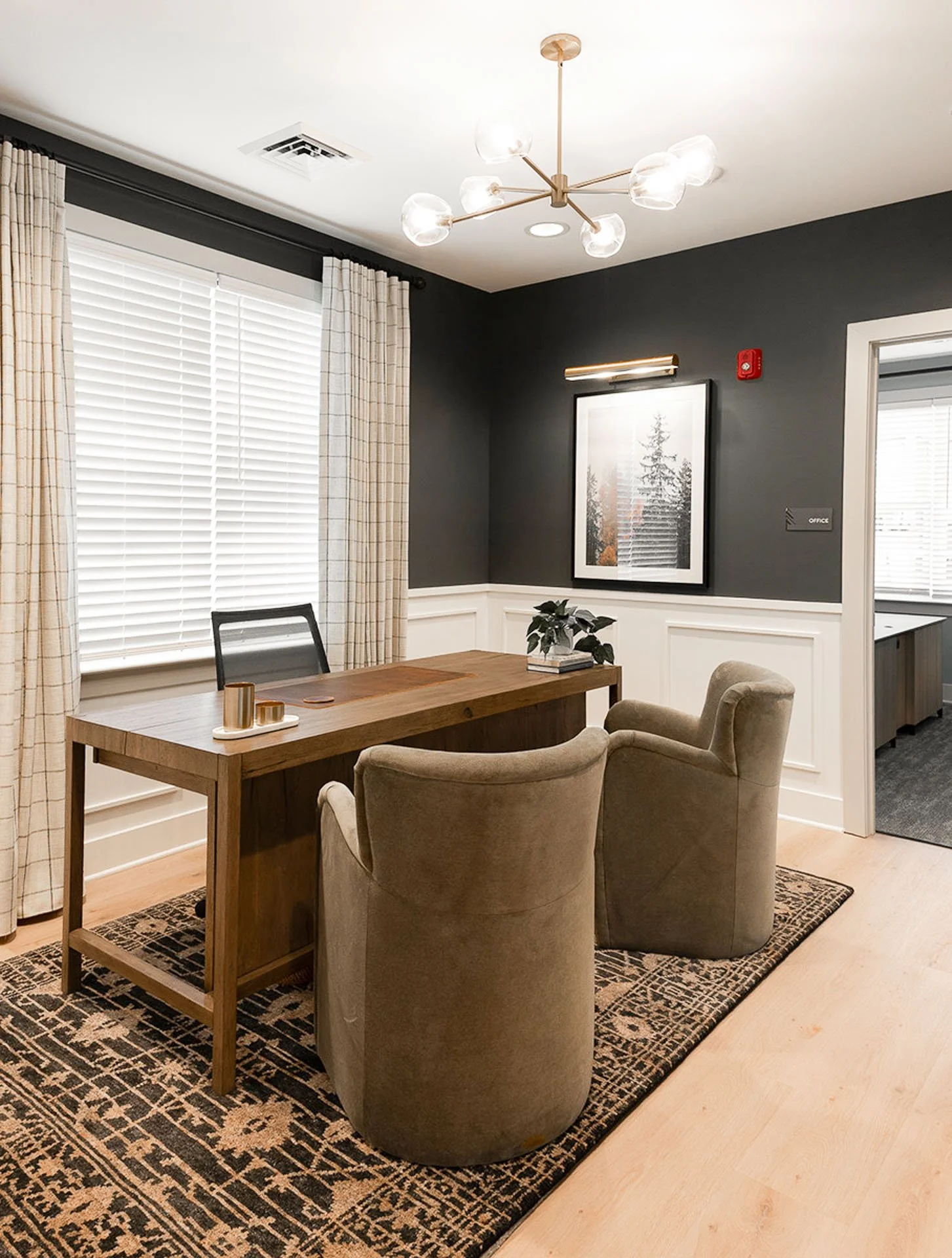 leasing office with dark walls, white paneling, and modern gold light fixture