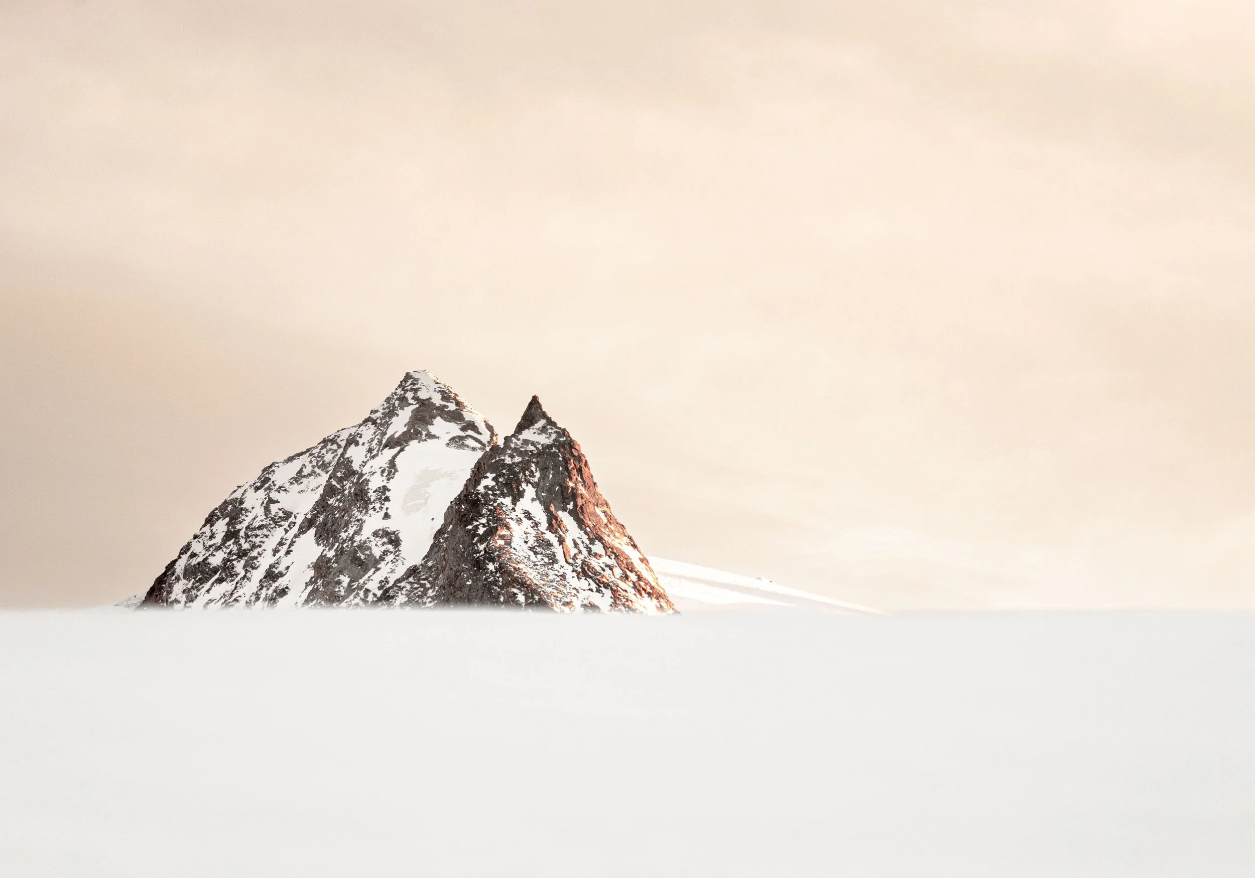 Montagne enneigée avec sommet rocheux, sur un fond de ciel clair