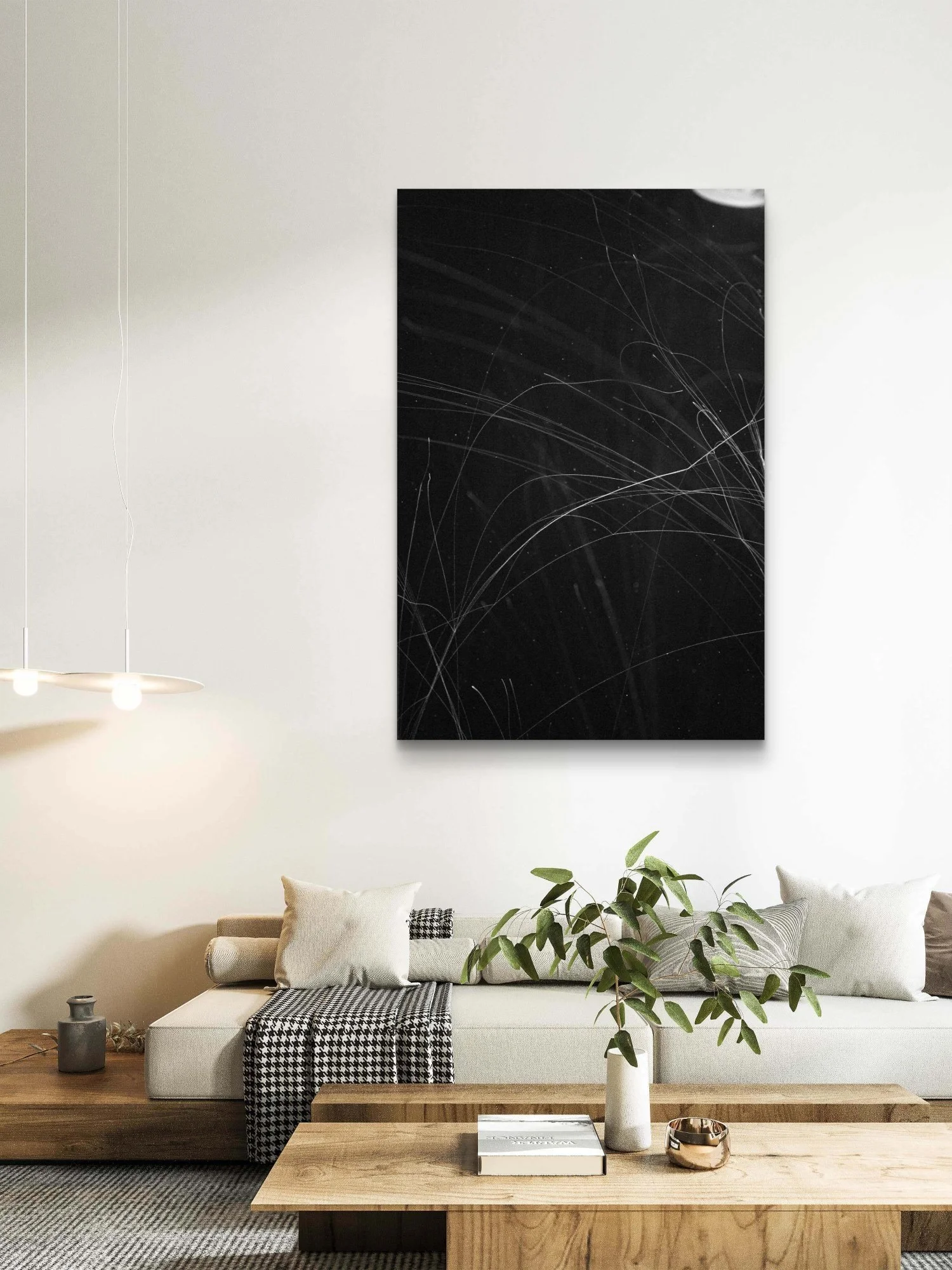 Salon moderne avec un canapé beige, coussins, une table basse en bois, plantes vertes, une peinture noire abstraite sur le mur et un éclairage suspendu