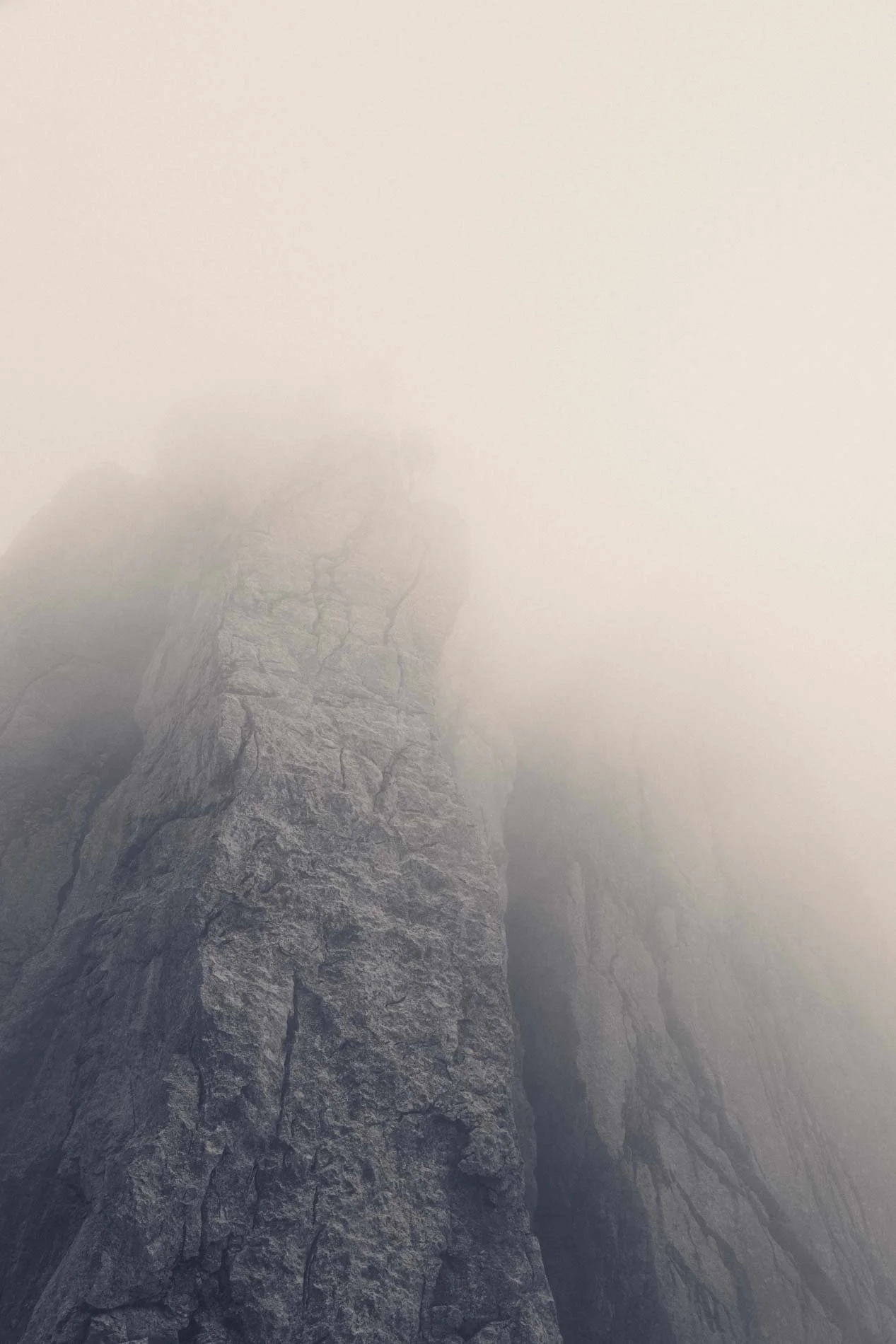 Une montagne rocheuse en partie couverte de brouillard.