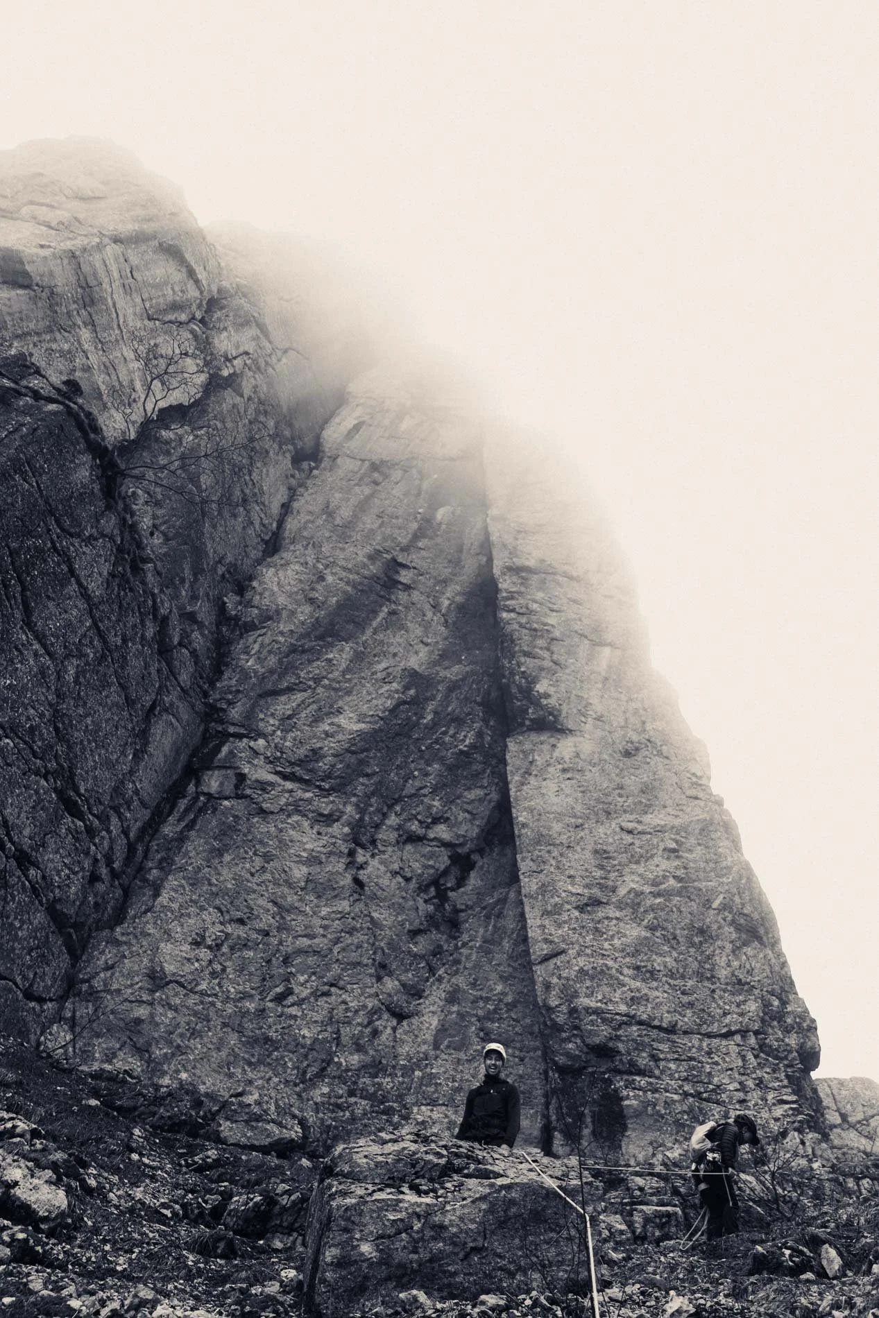 Des grimpeurs en escalade sur une falaise rocheuse avec brouillard.