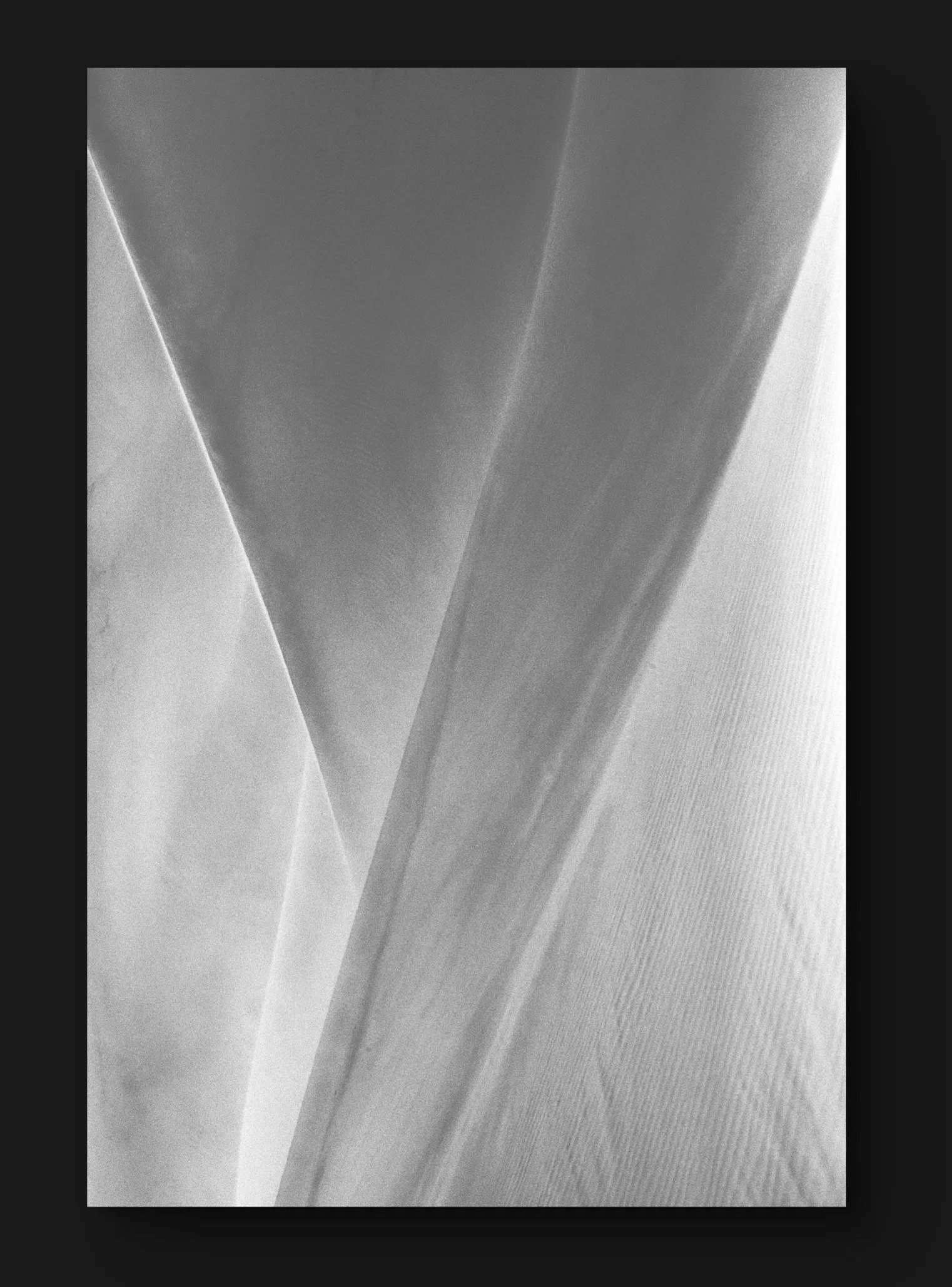Image en noir et blanc de plusieurs feuilles de papier ou de documents empilés ou chevauchants, avec des lignes de pliures ou de texturation visible.