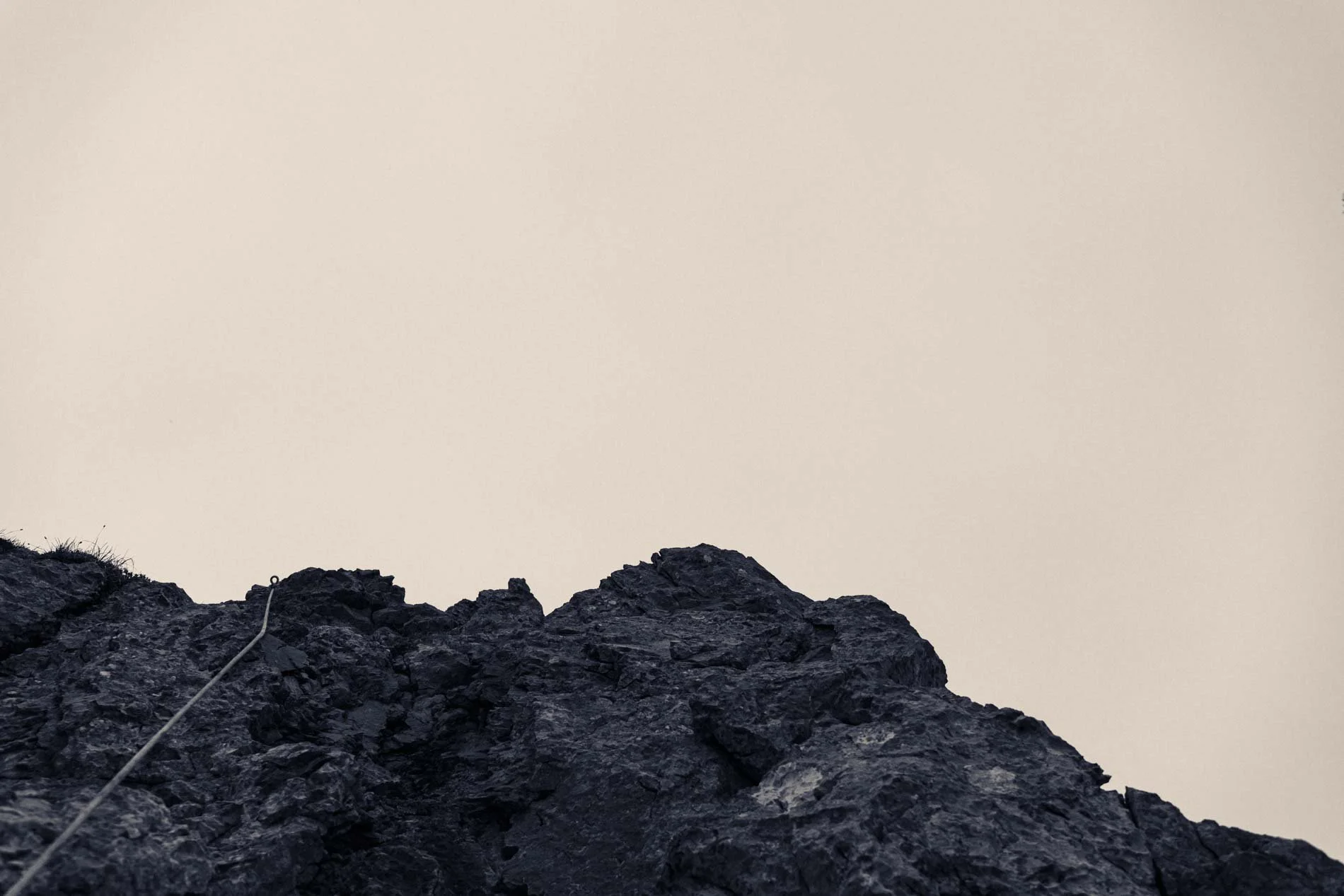 Vue d'en bas d'une roche noire contre un ciel beige clair.