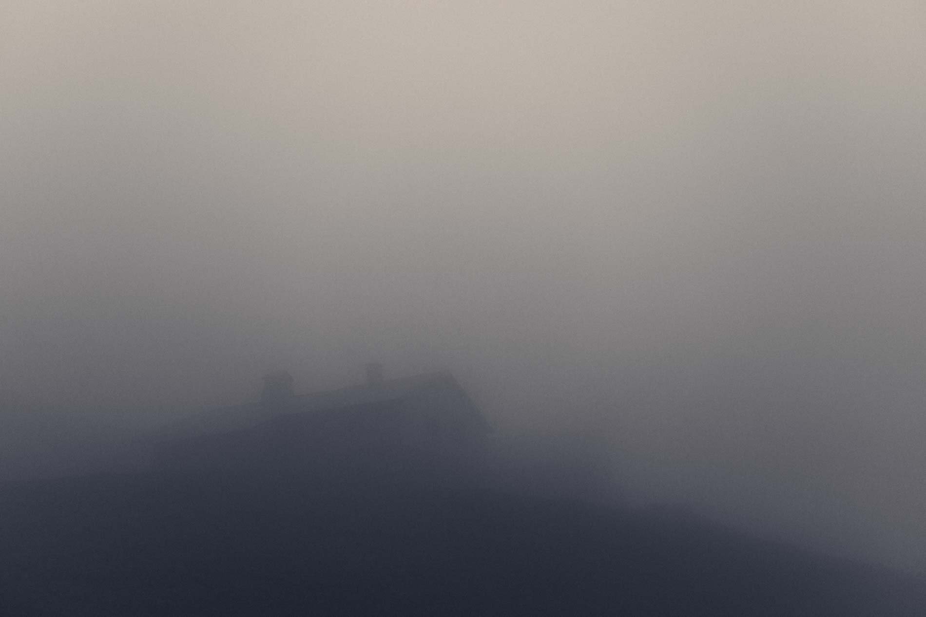 Paysage brumeux avec des montagnes lointaines et une faible visibilité.