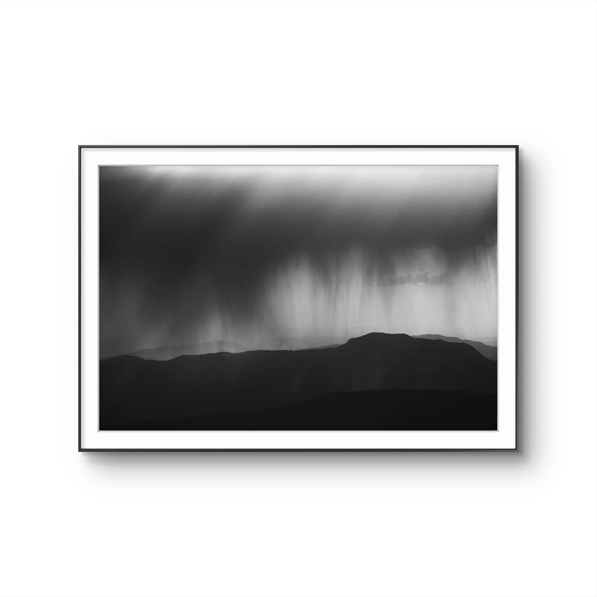 Un téléviseur noir et blanc affichant un paysage de montagnes en silhouette contre un ciel sombre.