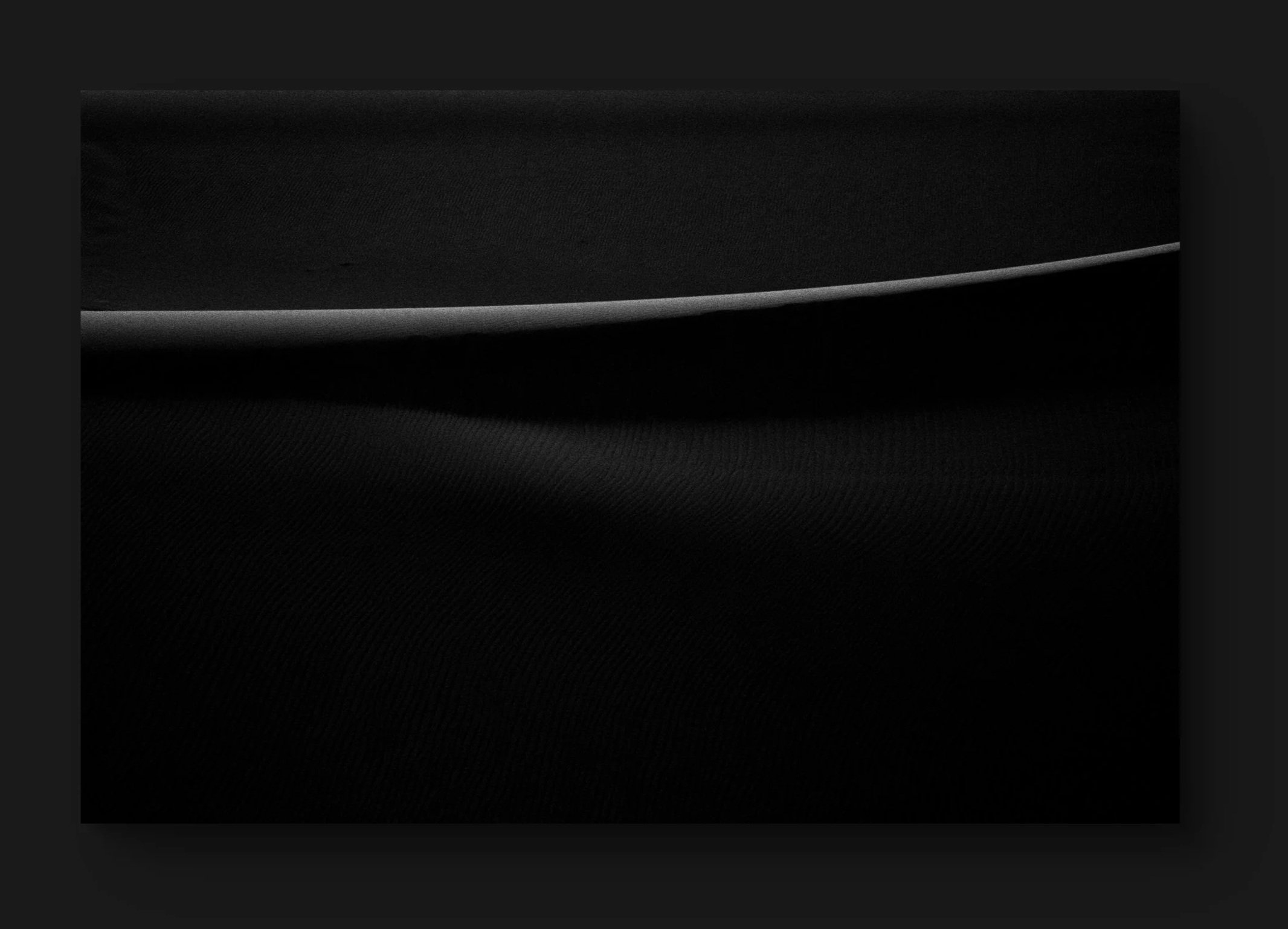 Une surface noire avec une fine ligne lumineuse courbe au centre.