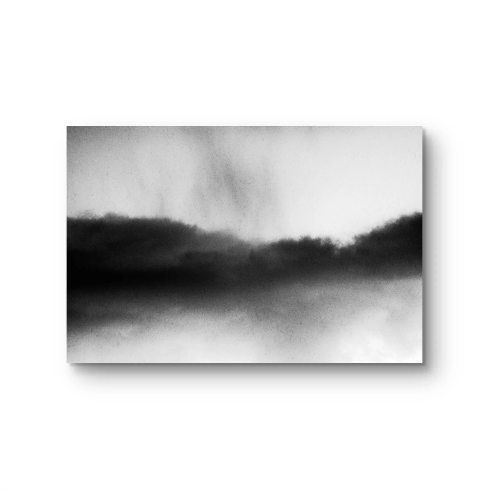 Photo en noir et blanc d'un paysage avec un ciel nuageux et des collines ou montagnes à l'horizon.
