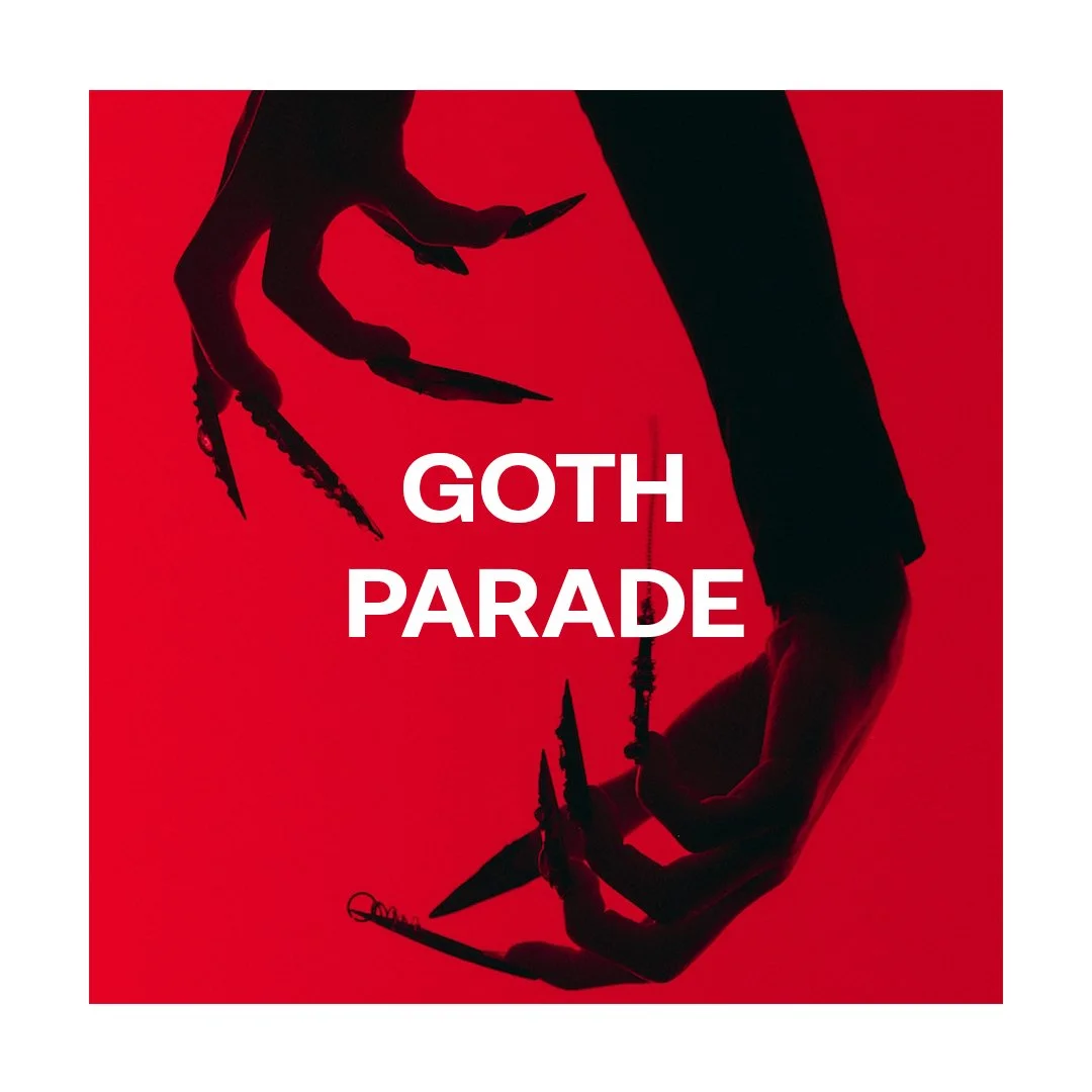 Silhouette of a hand with long, claw-like fingers holding a small dagger, set against a red background with the text 'GOTH PARADE' in white.