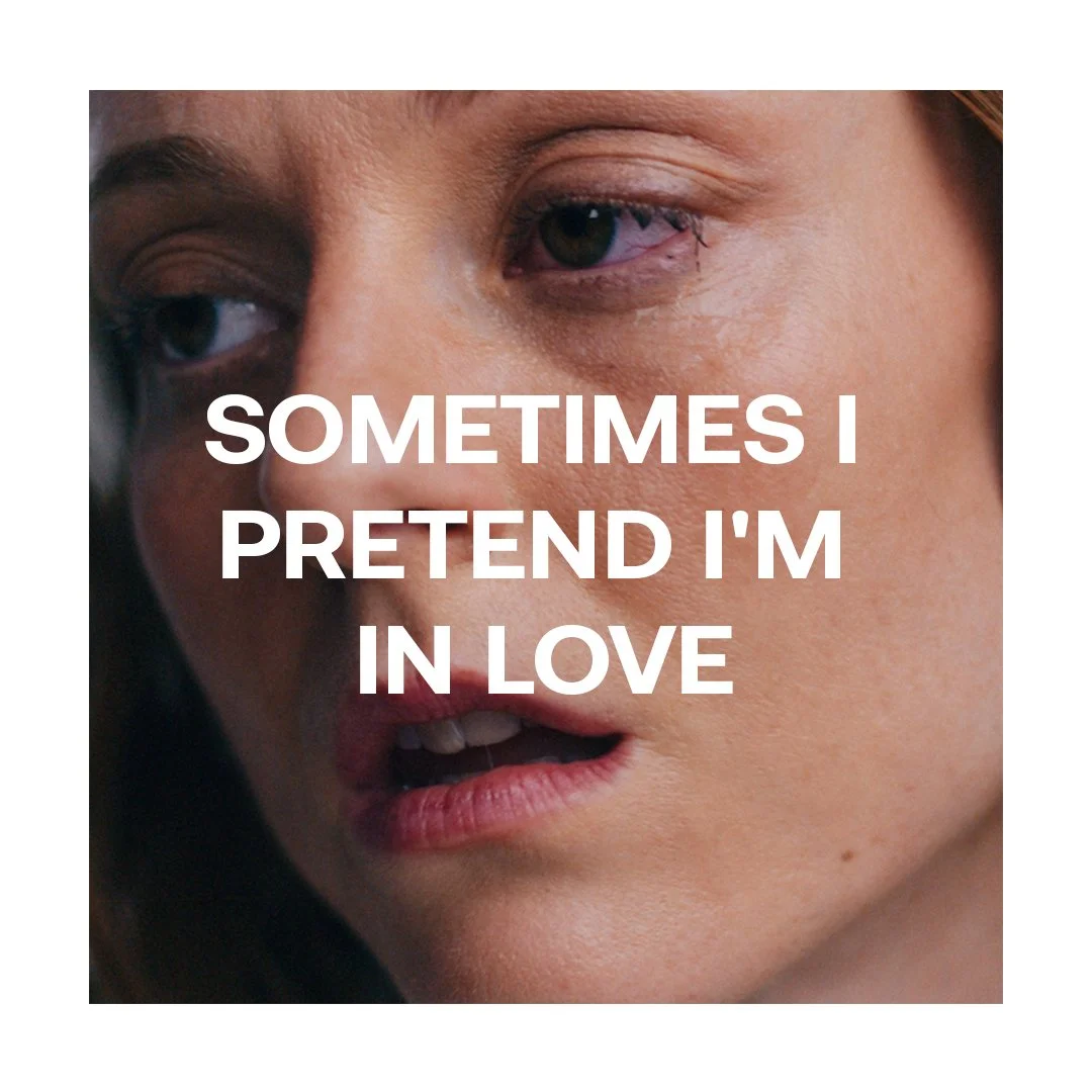 Close-up of a woman's face with slightly parted lips and a contemplative expression, overlaid with the text "Sometimes I pretend I'm in love."