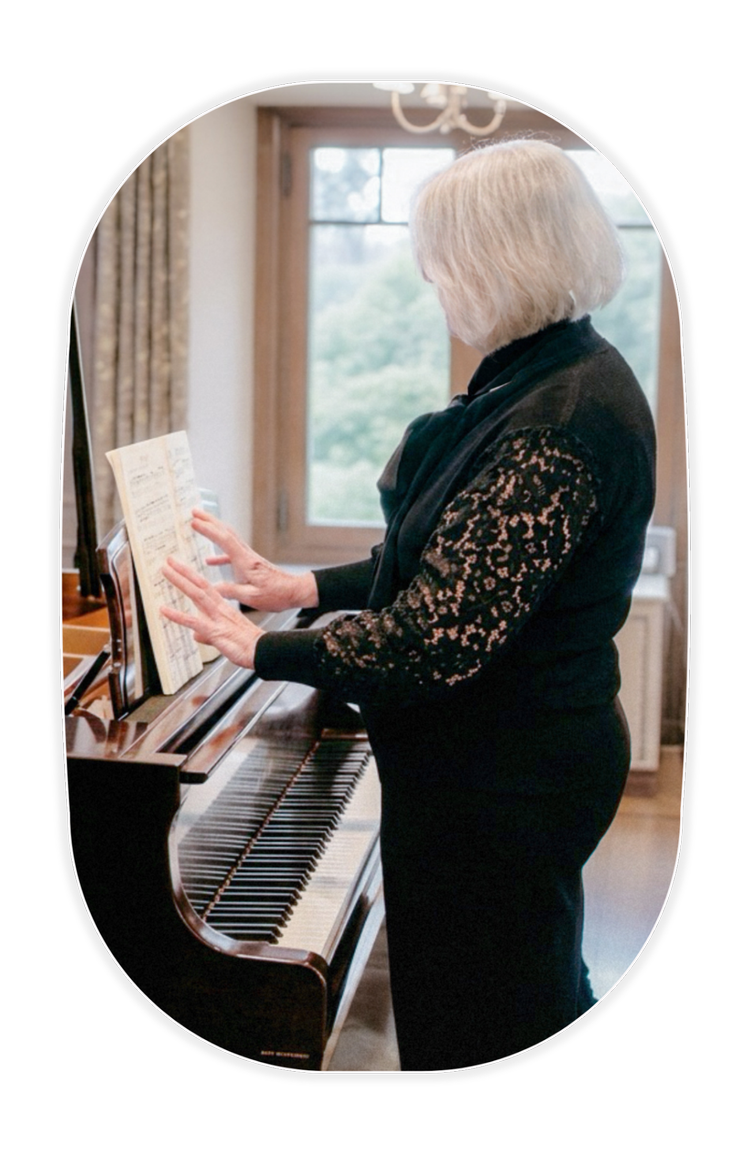 Amanda standing beside an acoustic piano with sheet music