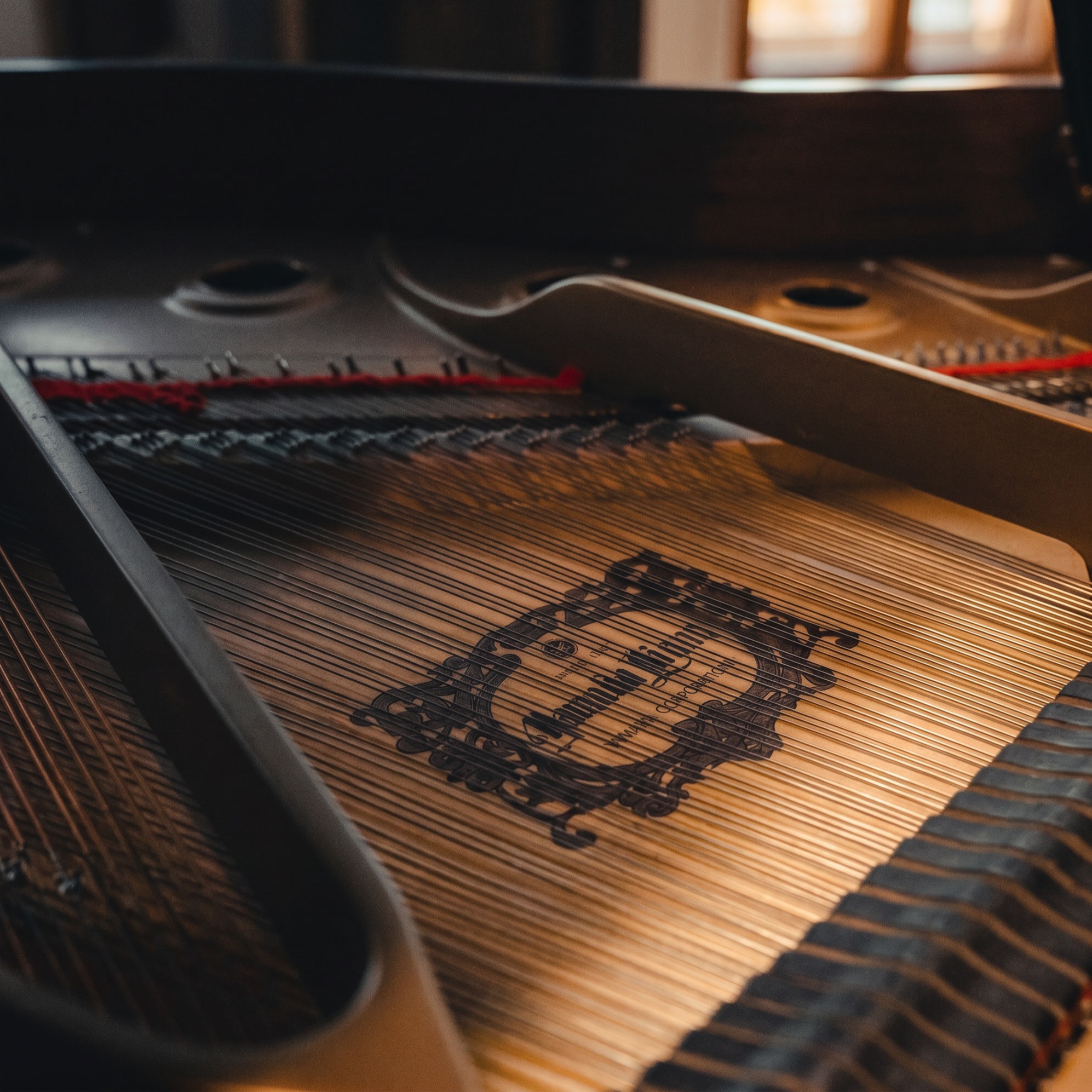 Close-up of a piano's internal strings and hammers with a warm light illuminating part of the instrument.
