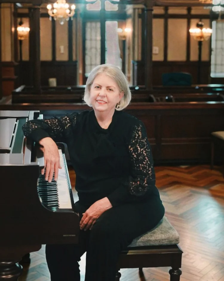 Amanda seated beside the piano