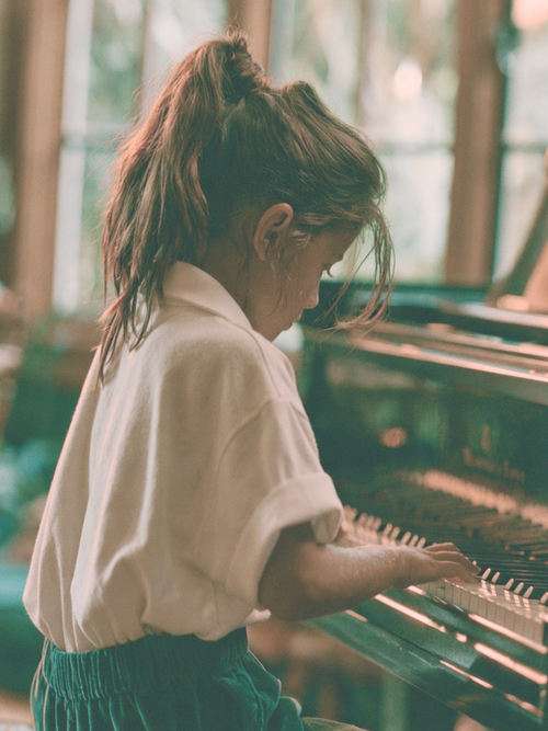 Student seated at the piano in natural light