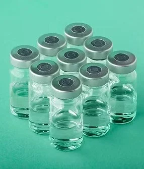 Ten small glass vials filled with clear liquid, arranged in a pyramid on a green background.