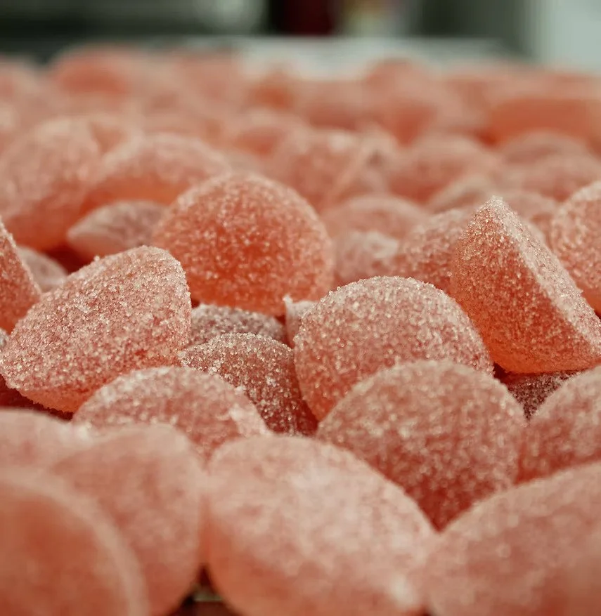 Close-up of orange gummy candies coated with sugar.
