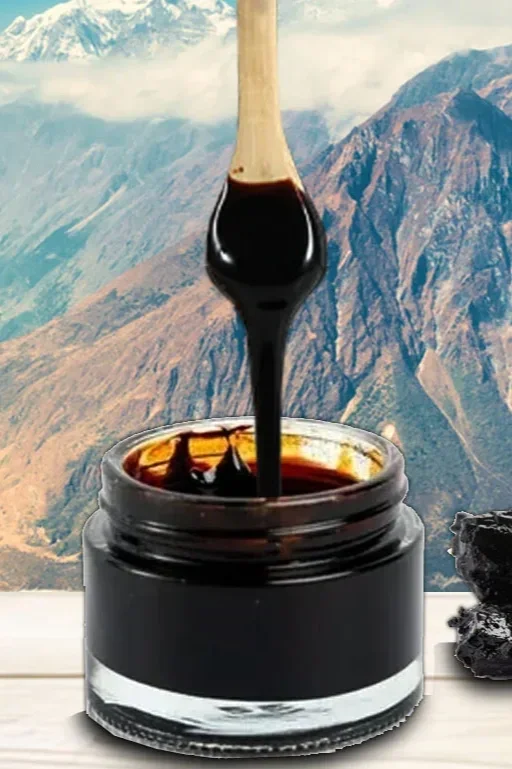 Close-up of black ink or gel being stirred with a wooden stick in a small glass jar, with a mountain landscape in the background.