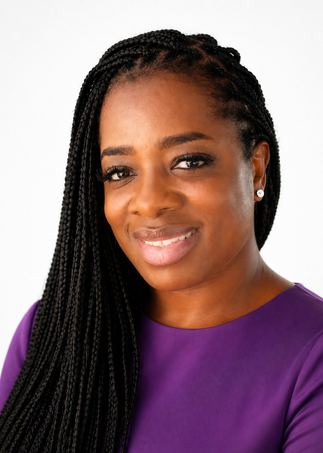Close-up portrait of an African-American woman with braided hair, smiling, wearing a purple top and diamond stud earrings.