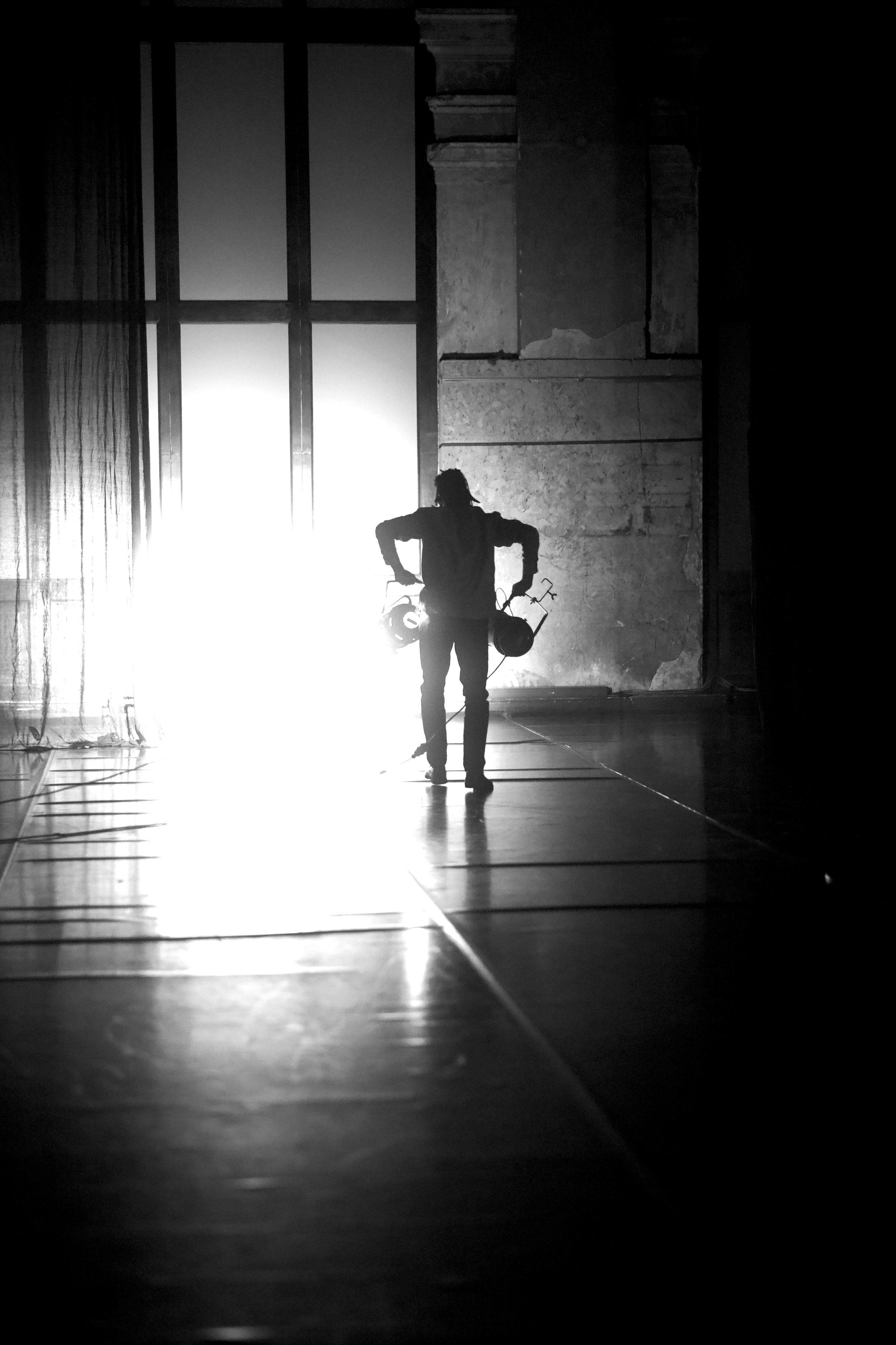 Silhouette einer Person mit Schlüssel in der Hand vor einem hellen Licht in einer alten, verzierten Wand in einem dunklen Raum.