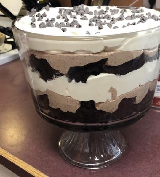 A layered chocolate and vanilla ice cream dessert in a glass bowl, topped with chocolate chips.