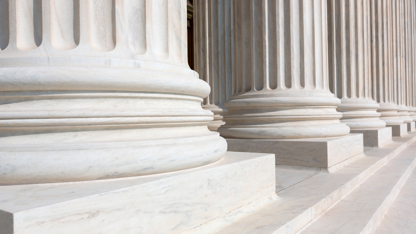 Close-up of classical marble columns with rounded bases and fluted shafts.