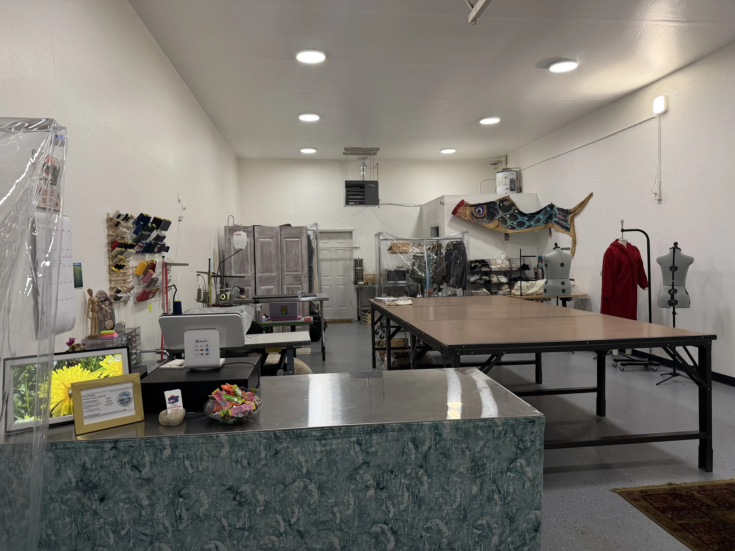 Interior of a craft or sewing store with tables, mannequins, fabric, and craft supplies.