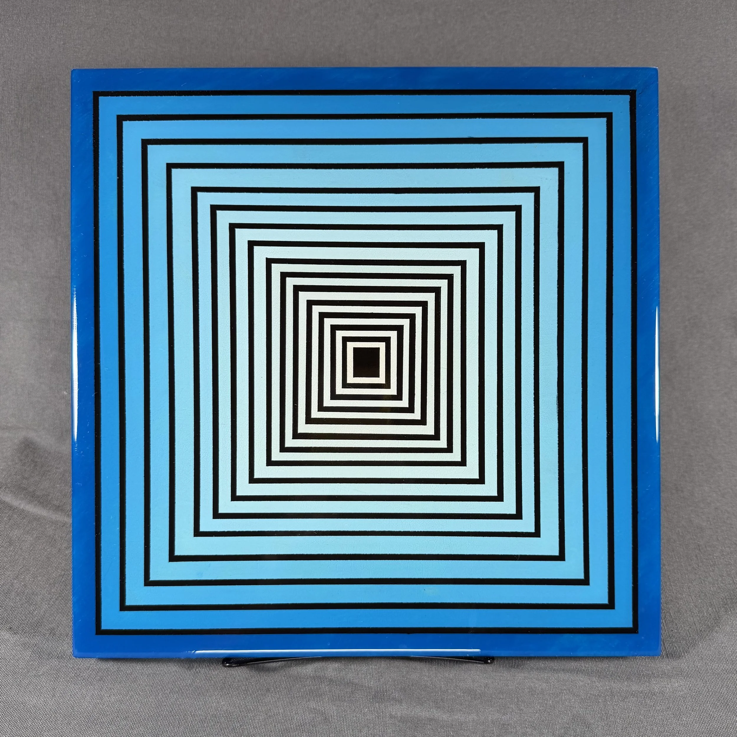 A blue and black maze puzzle with black lines on a blue background. The maze is square-shaped and appears to be an optical illusion or puzzle game.