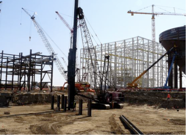Construction site with multiple cranes and steel framework for a building.
