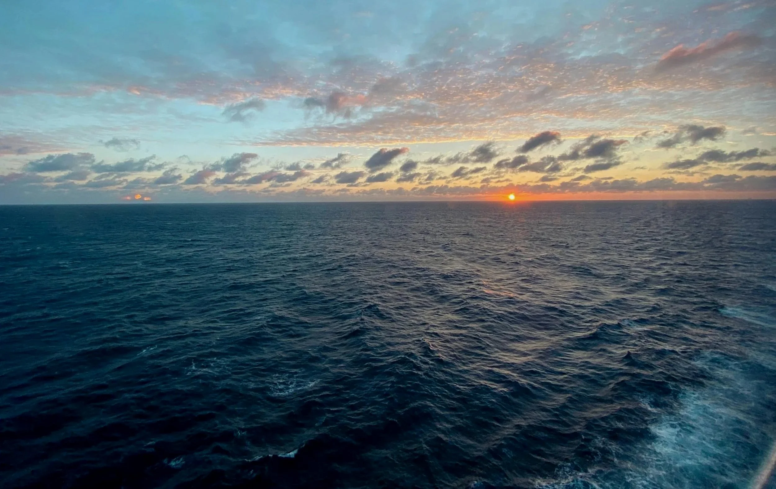 Sunset over the ocean with a partly cloudy sky
