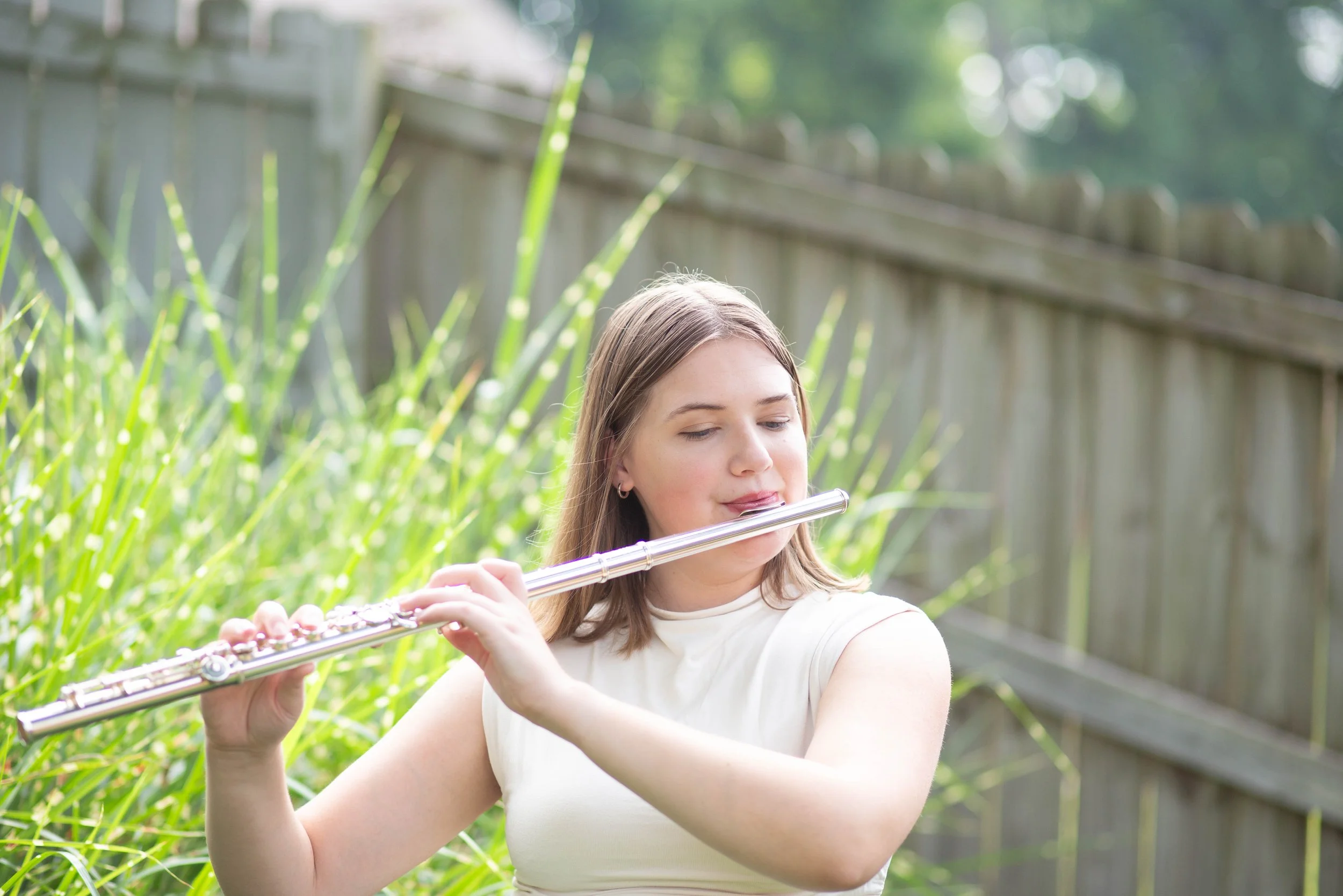 Lindsey Kovach playing the flute outdoors.