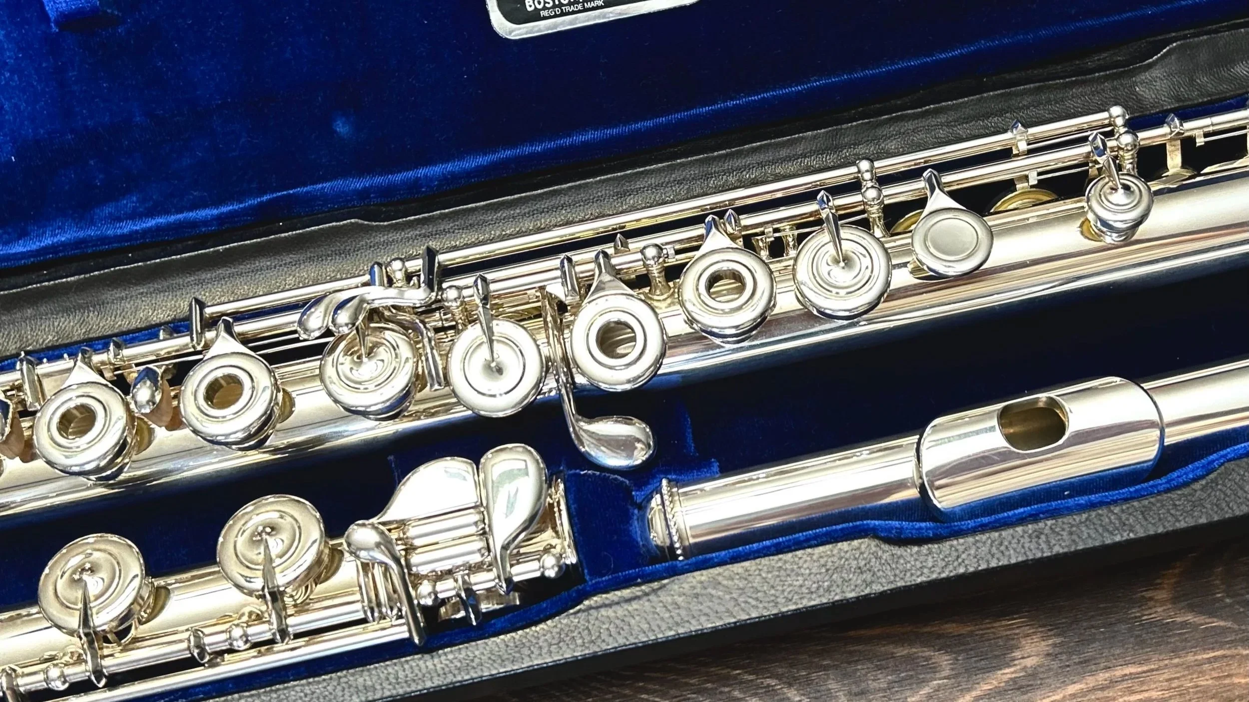 Close-up of a silver flute placed inside a case with a blue velvet lining.