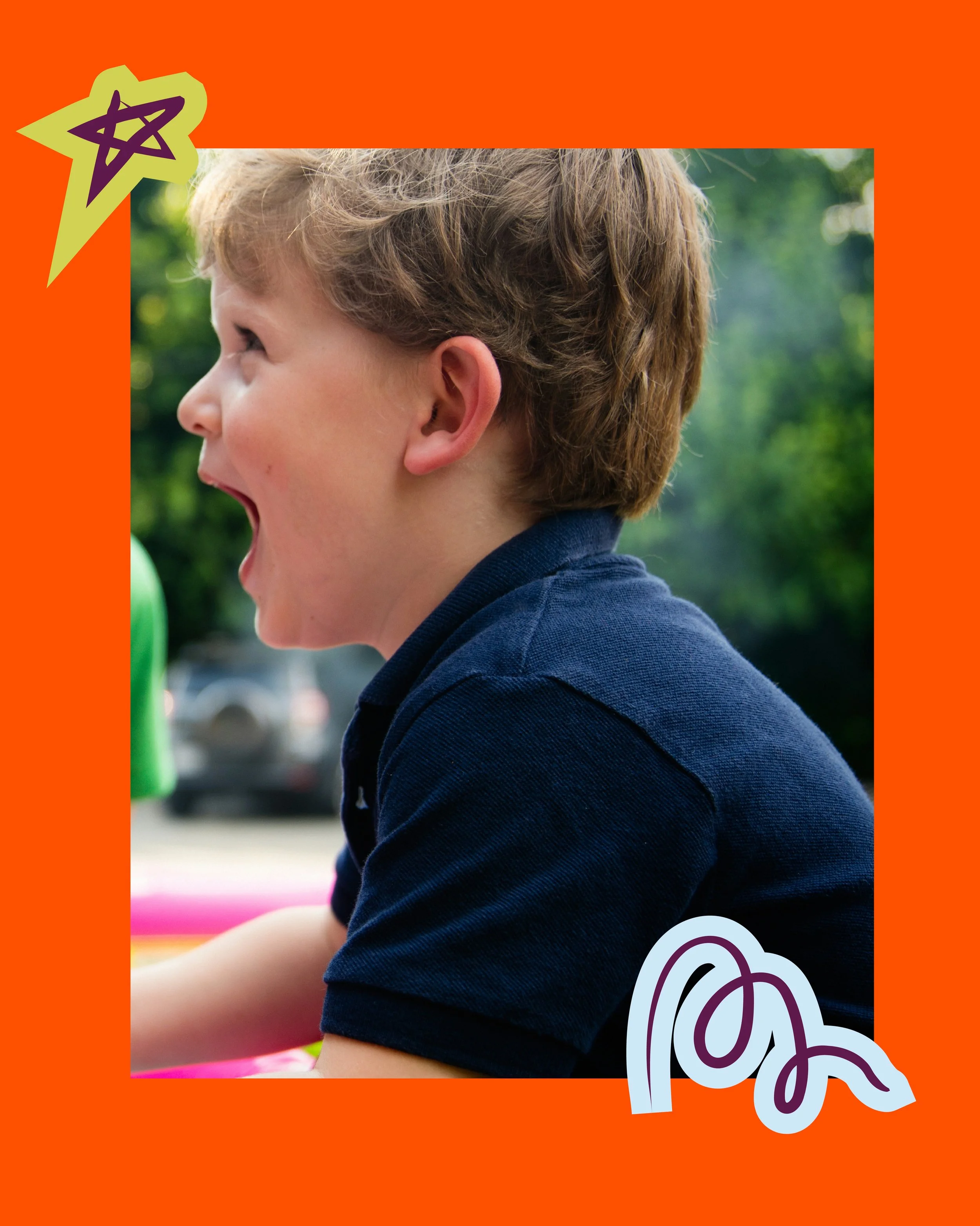Side profile of a young boy with curly light brown hair, open mouth, wearing a navy blue shirt, outdoors with blurred green trees and sunlight.