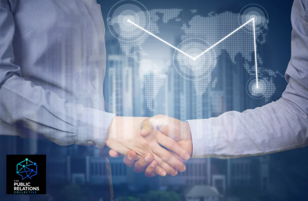 Two people shaking hands behind a computer