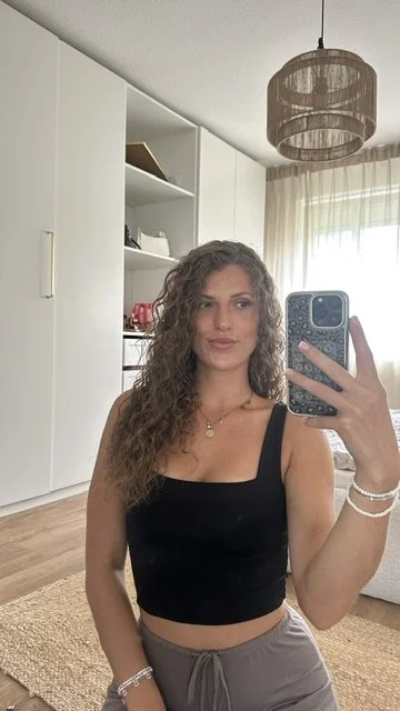 Michelle macht Selfie im Schlafzimmer mit weißen Wänden, Vorhängen und einer auffälligen Deckenleuchte.