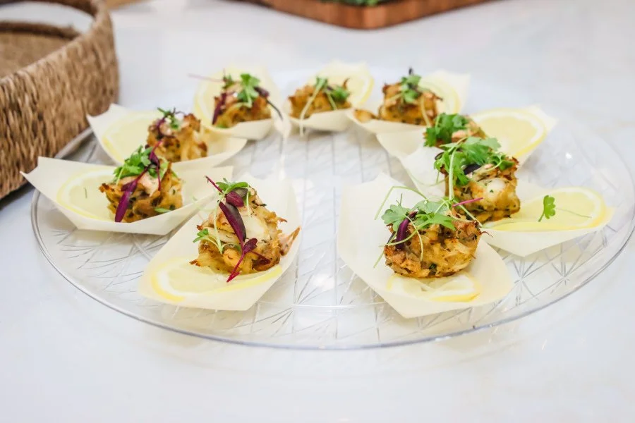 Appetizer with small fried food balls garnished with fresh herbs, served on lemon slices on a clear glass plate.