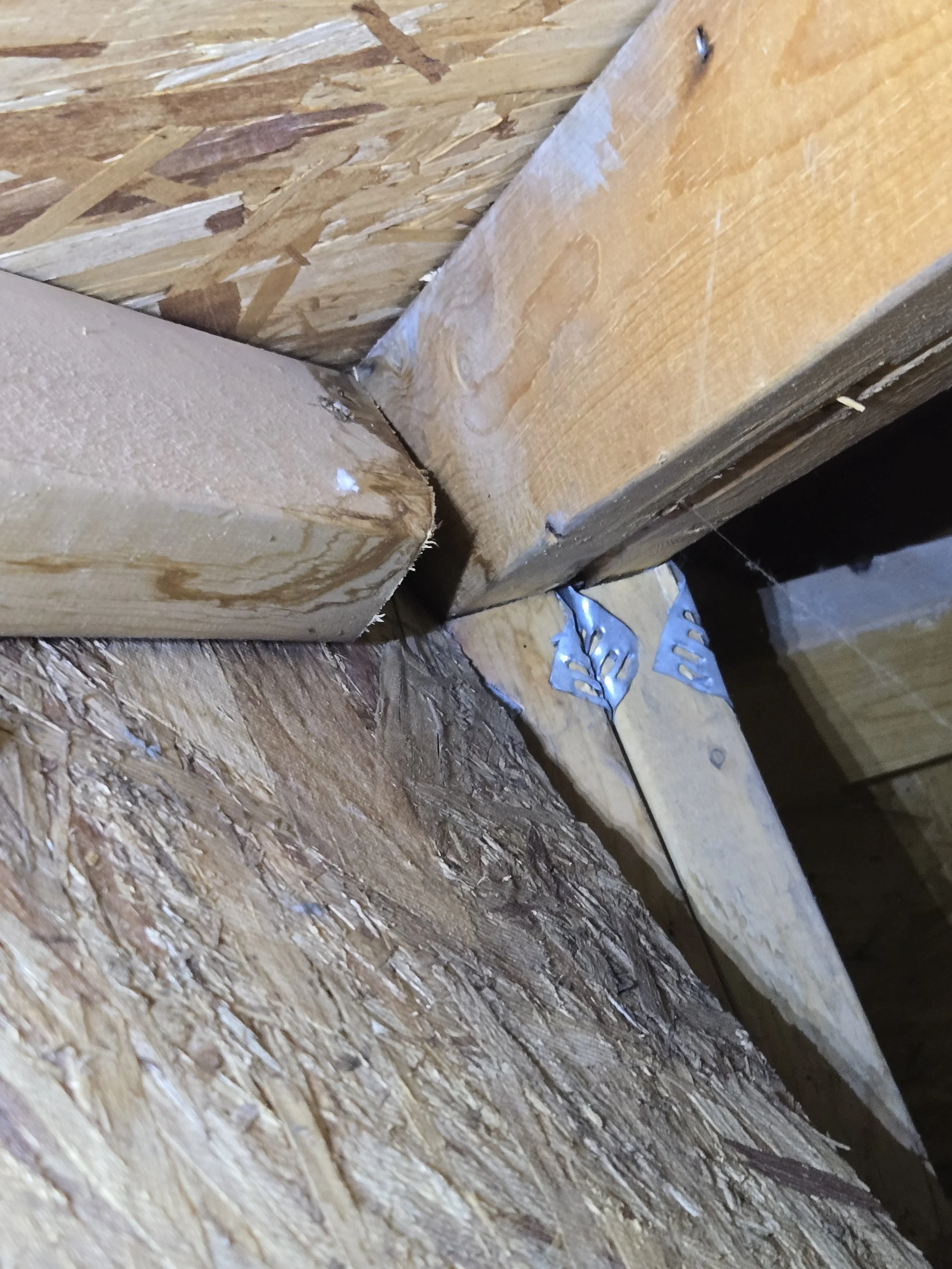 Close-up view of wooden construction materials, including OSB plywood and dimensional lumber, with metal fasteners.