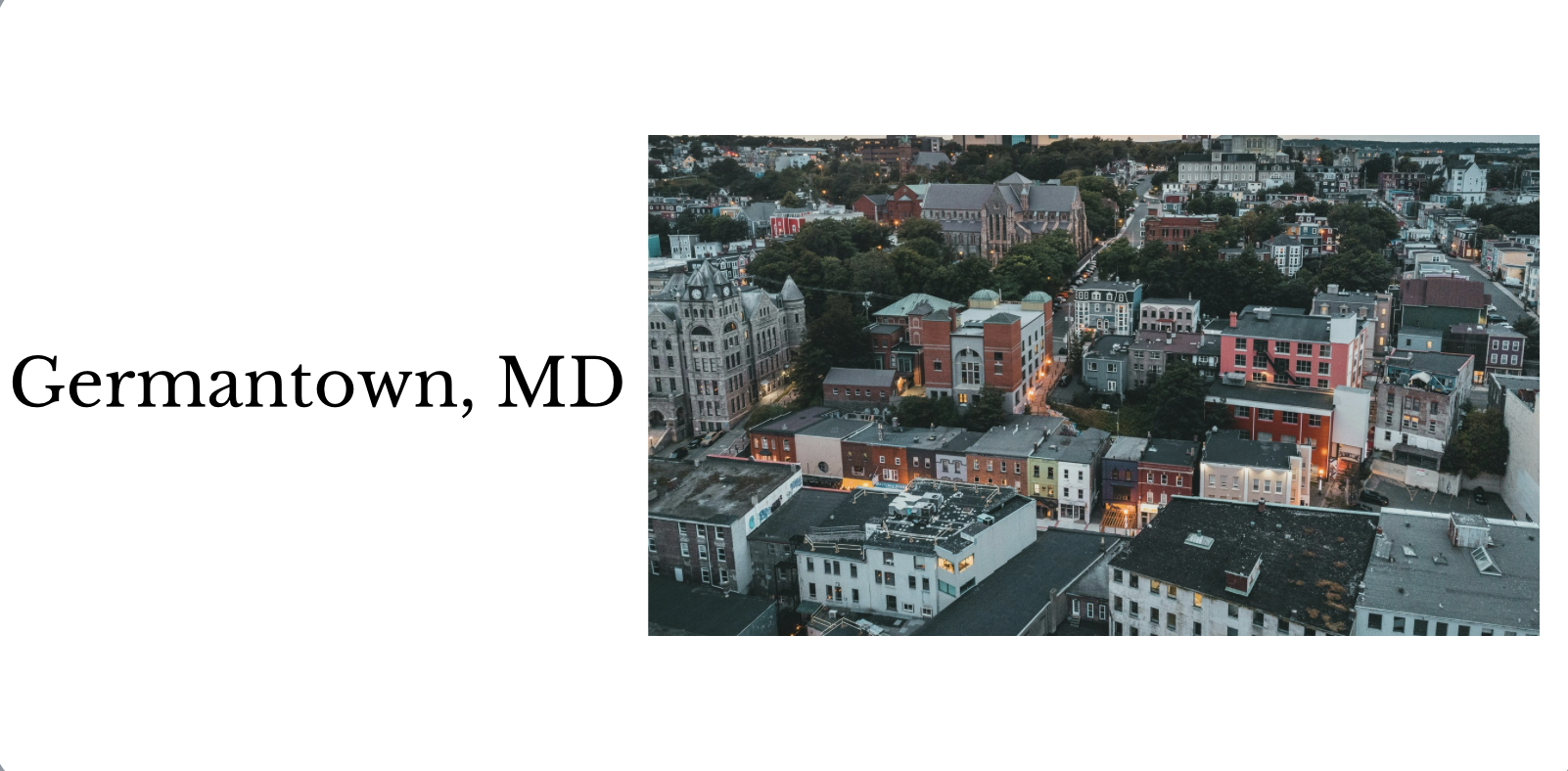 An aerial view of Germantown, Maryland, showing a mix of historic and modern buildings with streetlights illuminating the streets during dusk.