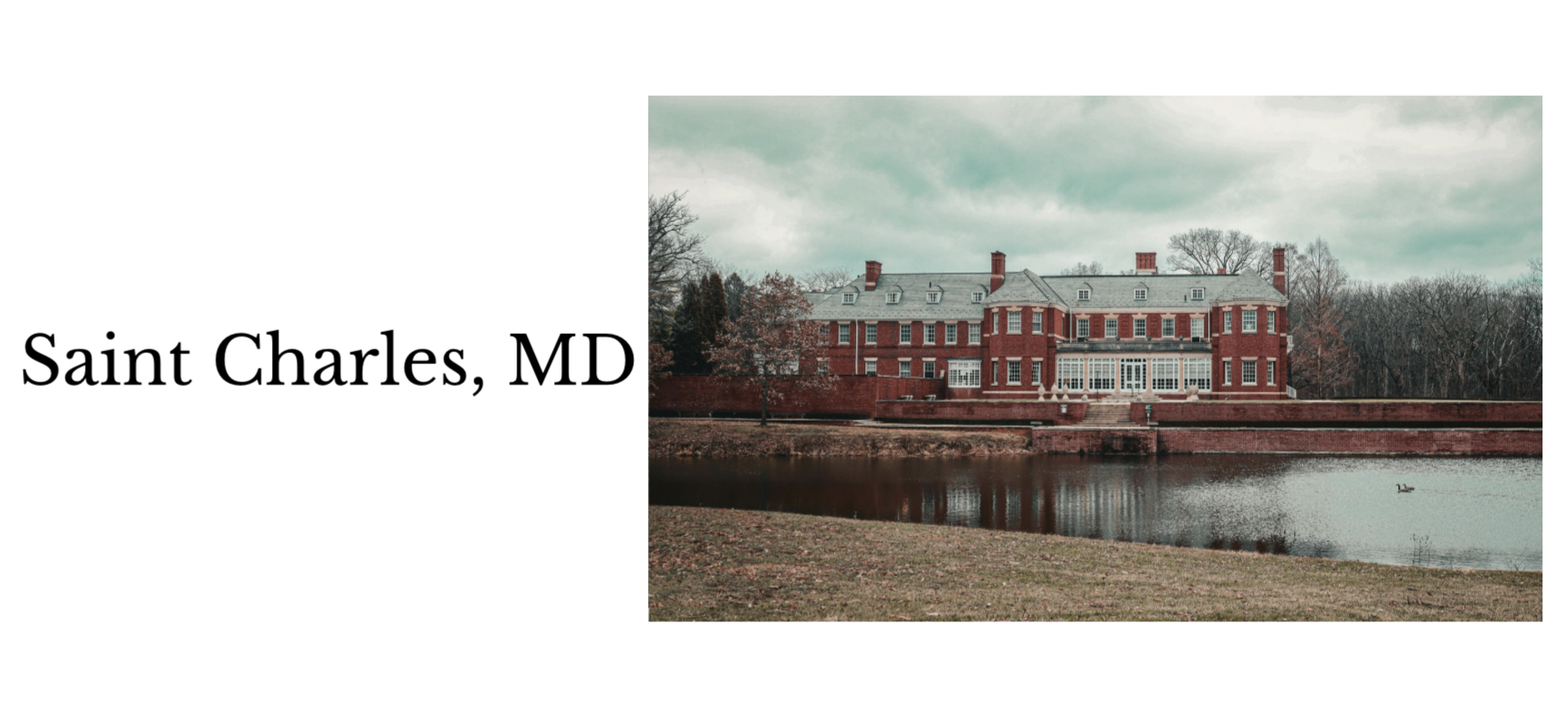 A historic red brick mansion with multiple windows and chimneys, situated next to a body of water with a duck swimming, surrounded by leafless trees under a cloudy sky in Saint Charles, Maryland.