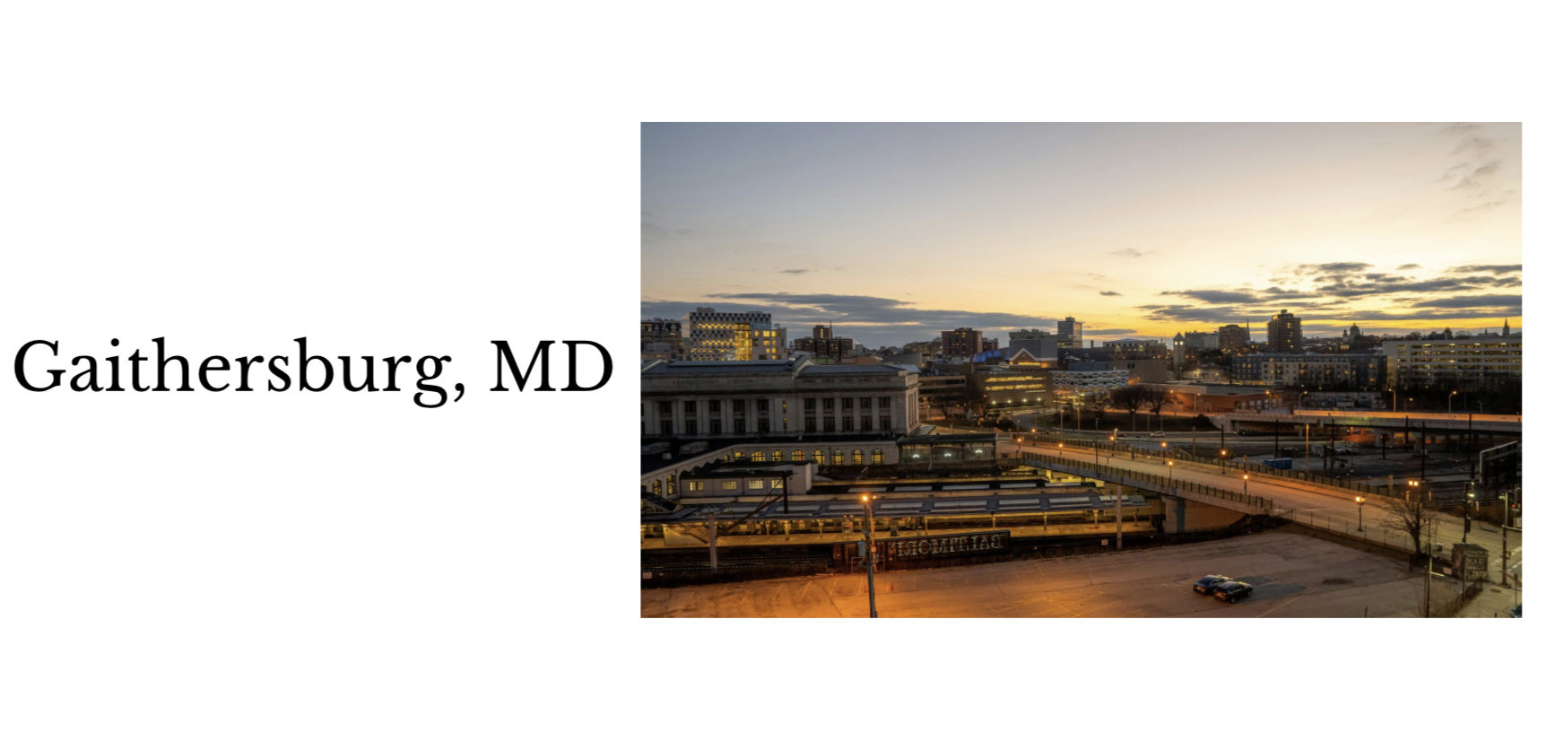 Sunset over downtown Gaithersburg, Maryland with illuminated buildings and train tracks in the foreground.
