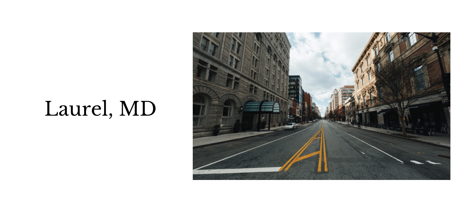 Empty city street with tall buildings, trees, and cloudy sky, located in Laurel, MD.