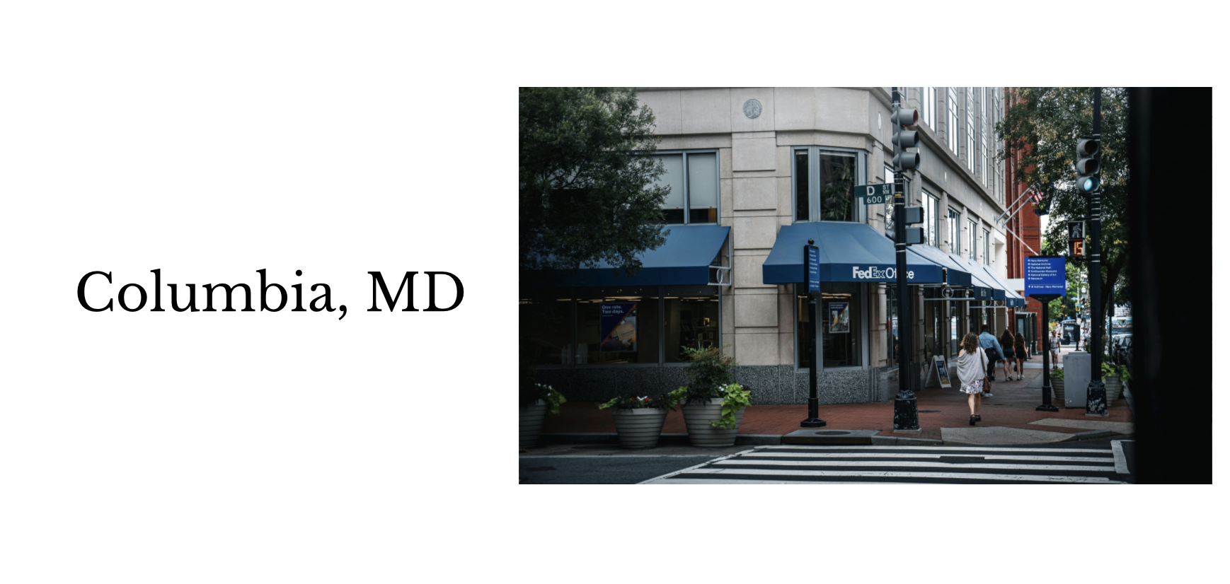 Street corner commercial building with blue awnings, street signs, and pedestrians in Columbia, MD