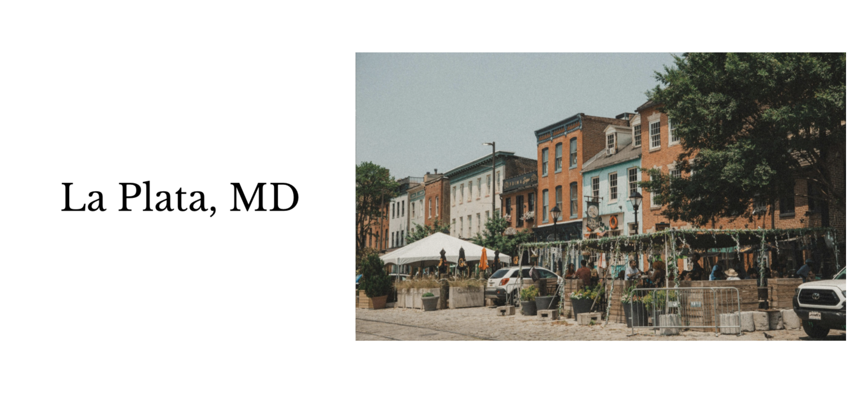 A lively outdoor scene in La Plata, MD with colorful historic buildings, people dining under umbrellas, and a tree providing shade.