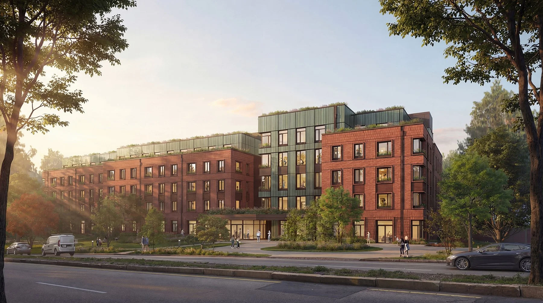 A modern multi-story apartment building with red brick and green siding exterior, surrounded by trees and a park, with cars and people walking near the entrance during daytime.